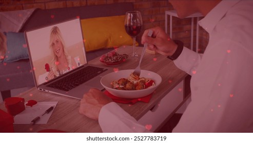 Caucasian couple enjoying virtual dinner date, boyfriend holding wine glass. Girlfriend appearing on laptop screen, both smiling warmly, surrounded by romantic decor - Powered by Shutterstock