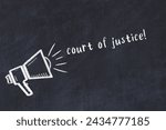 Chalk drawing of loudspeaker and handwritten inscription court of justice on black desk