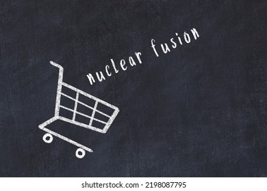 Chalk Drawing Of Shopping Cart And Word Nuclear Fusion On Black Chalboard. Concept Of Globalization And Mass Consuming.