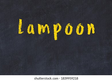 Chalk Handwritten Inscription Lampoon On Black Desk