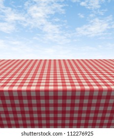 Checkered Tablecloth Table With A Blank Empty Picnic Cloth In Perspective On A Blue Sunny Summer Sky As A Symbol Of Food And Leisure Fun.