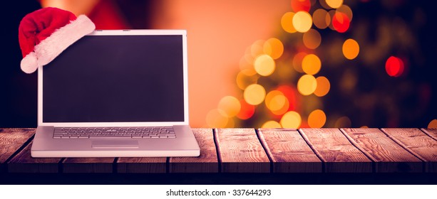 christmas laptop against desk with christmas tree in background - Powered by Shutterstock