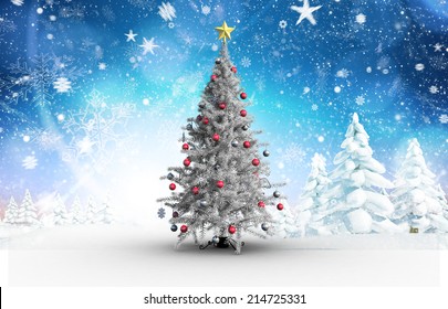 Christmas tree with baubles and star against snowy landscape with fir trees