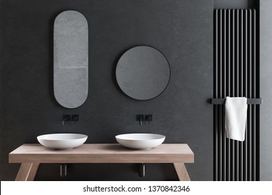 Close Up Of Double Bathroom Sink Standing On Wooden Counter In Modern Bathroom With Dark Gray Walls And Round And Oblong Mirrors. 3d Rendering