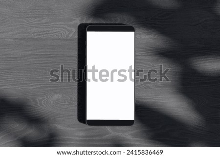 Close up of empty white smartphone on dark wooden surface with leaf shadows. Presentation concept. Mock up, 3D Rendering