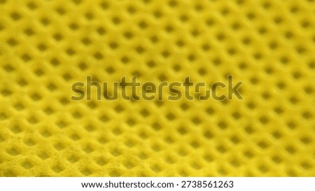 Close up of yellow plastic mesh texture with repetitive geometric grid pattern