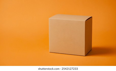 Closed cardboard box sits on a solid orange background. Premium packaging box mockup for displaying a marketing advertisement for a product.