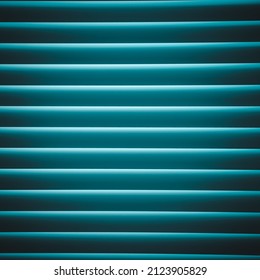 Closed window blinds close up. Closed room blinds. Window with blue turquoise jalousie. Horizontal blinds with illumination.