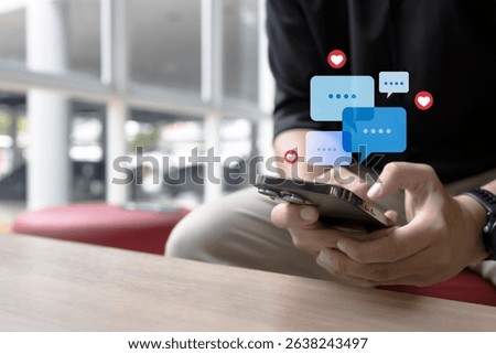 Close-up of a hand using smartphone with chat bubbles and heart icons, representing online communication and social media