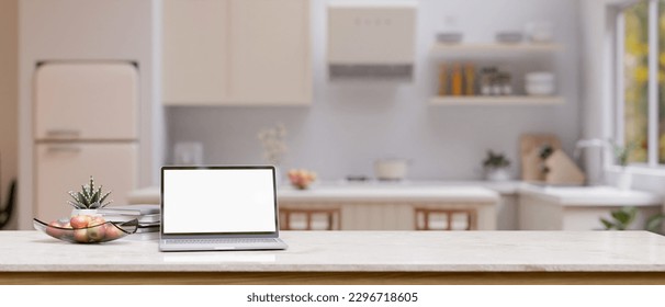 Close-up image, A tabletop with laptop computer white screen mockup, apple tray, decor plant and copy space over blurred background of minimal white kitchen. 3d render, 3d illustration