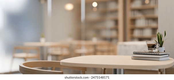 A close-up image of a wooden table features copy space, books, a coffee cup, and a decorative plant in a beautiful, cozy contemporary coffee shop. 3d render, 3d illustration - Powered by Shutterstock