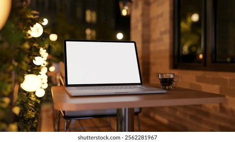 A close-up of a laptop with a white screen mockup and a coffee cup on a table on an apartment balcony of a cafe at night, illuminated by bulk lights. 3d render, 3d illustration - Powered by Shutterstock