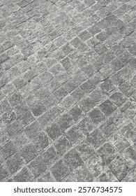 A close-up view of a cobblestone surface with uniform grayish tones and natural stone textures, perfect for architectural backgrounds or pavement design projects