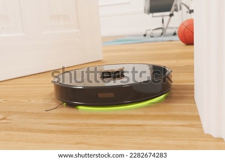 Close-up view of the smart cleaning robot racing through the whole home area. Detecting and avoiding obstacles at a high speed. Removing dust and clean wooden floor. Remote controlled. Self-driving.