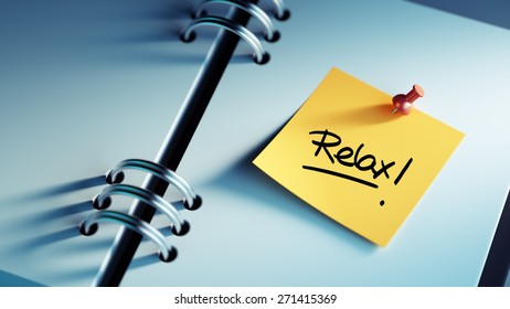 Closeup Yellow Sticky Note paste it in a notebook setting an appointment. The words Relax written on a white notebook to remind you an important appointment.