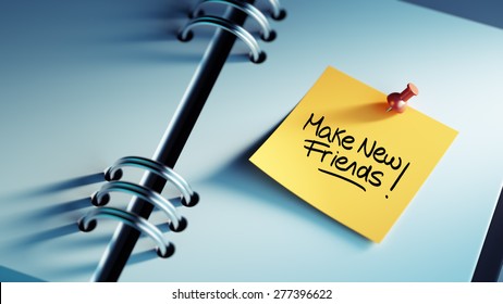 Closeup Yellow Sticky Note paste it in a notebook setting an appointment. The words Make new friends written on a white notebook to remind you an important appointment.