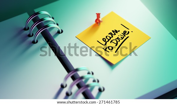 Closeup Yellow Sticky Note\
paste it in a notebook setting an appointment. The words Learn to\
Drive written on a white notebook to remind you an important\
appointment.