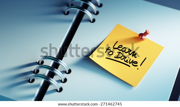 Closeup Yellow Sticky Note
paste it in a notebook setting an appointment. The words Learn to
Drive written on a white notebook to remind you an important
appointment.