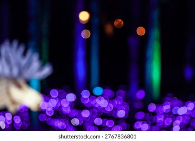 A cluster of soft circular lights in vivid hues blends with elongated bright lines in the background, forming an abstract composition with a festive, nighttime atmosphere.Multicolored bokeh with purple highlights and vertical luminous streaks.