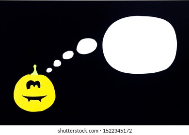 A colored background from a pumpkin cut out of orange paper isolated on a black background with a place for notes, ideal for the holiday of all saints - Halloween.