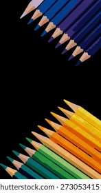 Colored pencils in two diagonal rows facing each other on a black background, featuring blue, purple, yellow, orange, and green hues.