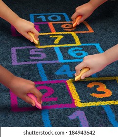 Community Development Education And Children Learning Concept With A Group Of Hands As Ethnic Groups Of Young People Holding Chalk Cooperating Together As Friends To Draw A Playground Hopscotch Game.