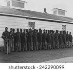 Company E, 4th U.S. Colored Infantry, were part of the defending forces of Washington, D.C. Photo shows two rows of African Americans holding rifles at Fort Lincoln in 1864.