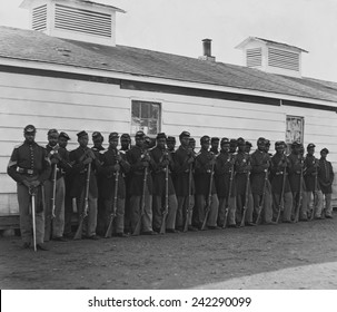 Company E, 4th U.S. Colored Infantry, were part of the defending forces of Washington, D.C. Photo shows two rows of African Americans holding rifles at Fort Lincoln in 1864.