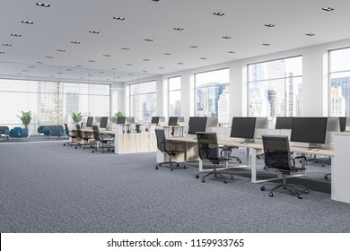 Company Office Corner With A Gray Carpet And Rows Of White Computer Desks. Industrial Style Interior With White Walls And Large Windows With A Cityscape. 3d Rendering Mock Up