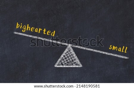 Concept of balance between bighearted and small. Black chalboard with sketch of scales and words on it