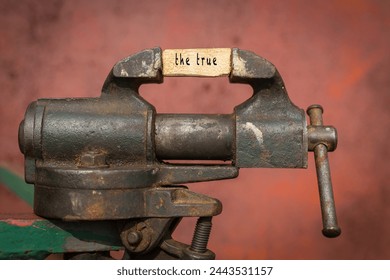 Concept of dealing with problem. Vice grip tool squeezing a plank with the word the true