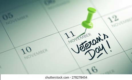 Concept image of a Calendar with a green push pin. Closeup shot of a thumbtack attached. The words Veteran's Day written on a white notebook to remind you an important appointment.