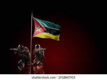 Concept Of Military Conflict With Soldier Statues And Waving National Flag Of Mozambique. Illustration Of Coup Idea. Two Guards Defending The Symbol Of Country Against Red Wall. 3D Illustration