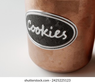 A concept showing two copper cookie jar tins with a metal embossed label on a white studio background - 3D