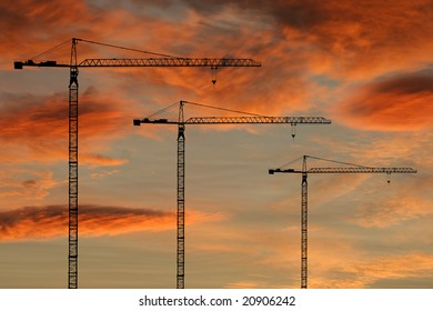 Construction cranes at sunset with colorful clouds