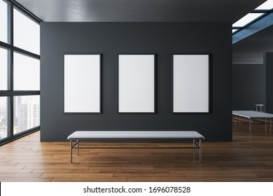 Contemporary exhibition hall interior with three empty poster on concrete wall, wooden floor, city view and daylight. Gallery concept. Mock up, 3D Rendering