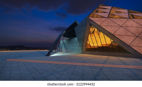 Contemporary Triangle Shape Design Modern Architecture Building Exterior With Glass, Concrete And Steel Element. Night Scene. Photorealistic 3D Rendering.