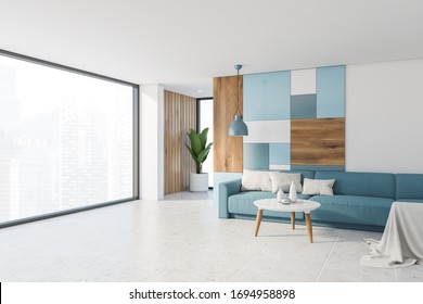 Corner Of Bright Panoramic Living Room With White And Colorful Pattern Wall, Tiled Floor, Comfortable Blue Sofa And Round Coffee Table. Window With Blurry Cityscape. 3d Rendering