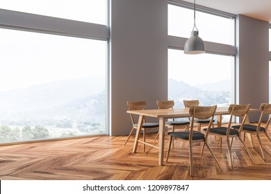 Corner of dining room with gray walls, wooden floor, long table with chairs and big windows with mountain view. 3d rendering