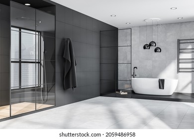 Corner Of Grey And Black Bathroom Interior With Oval Bathtub, Pendant Lamps, Steel Details, Framed Glass Partitions And Shower Cabin. Tiles. Modern Apartment Design Concept. 3d Rendering