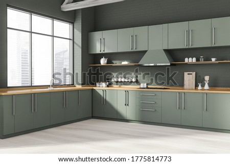 Corner of stylish kitchen with gray brick walls, wooden floor, gray and wooden cupboards and countertops with built in sink and cooker. Window with blurry cityscape. 3d rendering