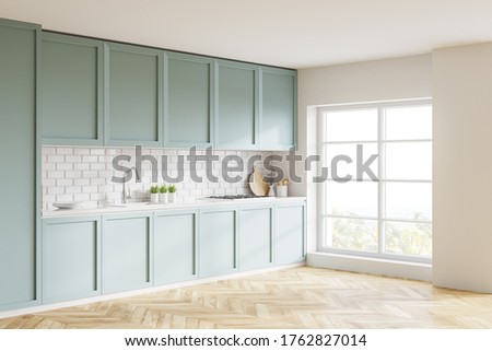 Corner of stylish kitchen with white and brick walls, wooden floor, blue countertops and cupboards with built in sink and cooker and blurry tropical view. 3d rendering