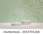 Cosmetic display product stand. Two terrazzo stone cylinder podium on pastel green background with palm leaf shadow. 3D rendering illustration