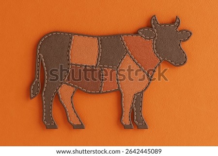 Craft And Farm Concept. Patchwork Cow Silhouette Made Of Leather Textures In Brown And Orange Tones On an Ornage Leather Background. 3d Rendering