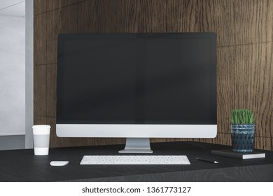 Creative designer desktop with empty computer screen, coffee cup and supplies on wooden wall background. Mock up, 3D Rendering 