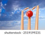 Cricket ball hitting wicket stumps against blue sky background. 3d-rendering