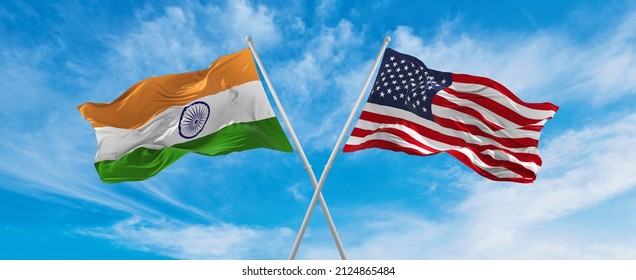 Crossed National Flags Of India And United States Of America Flag Waving In The Wind At Cloudy Sky. Symbolizing Relationship, Dialog, Travelling Between Two Countries. Copy Space. 3d Illustration