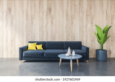 Dark Blue Sofa With Yellow Pillows In Black And Wooden Living Room, Wooden Wall. Minimalist Couch And Blue Coffee Table With Dishes, Plant, 3D Rendering No People