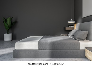 Dark gray bedroom interior with a concrete floor, a king size bed and a frame vertical poster hanging above it. A side view 3d rendering mock up - Shutterstock ID 1100462354