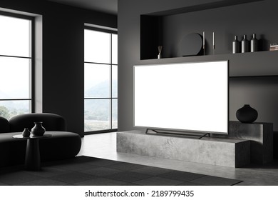 Dark Lounge Interior With Sofa And Tv On A Concrete Stand, Side View, Chill Space With Shelf And Art Decoration. Panoramic Window On Countryside. Mock Up Blank Tv Display. 3D Rendering